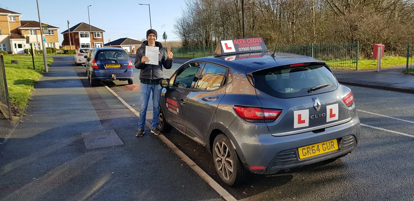 One of Alex's pupils holding his pass certificate beside the car