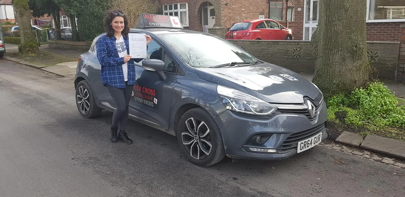 One of Alex's pupils holding her pass certificate beside the car