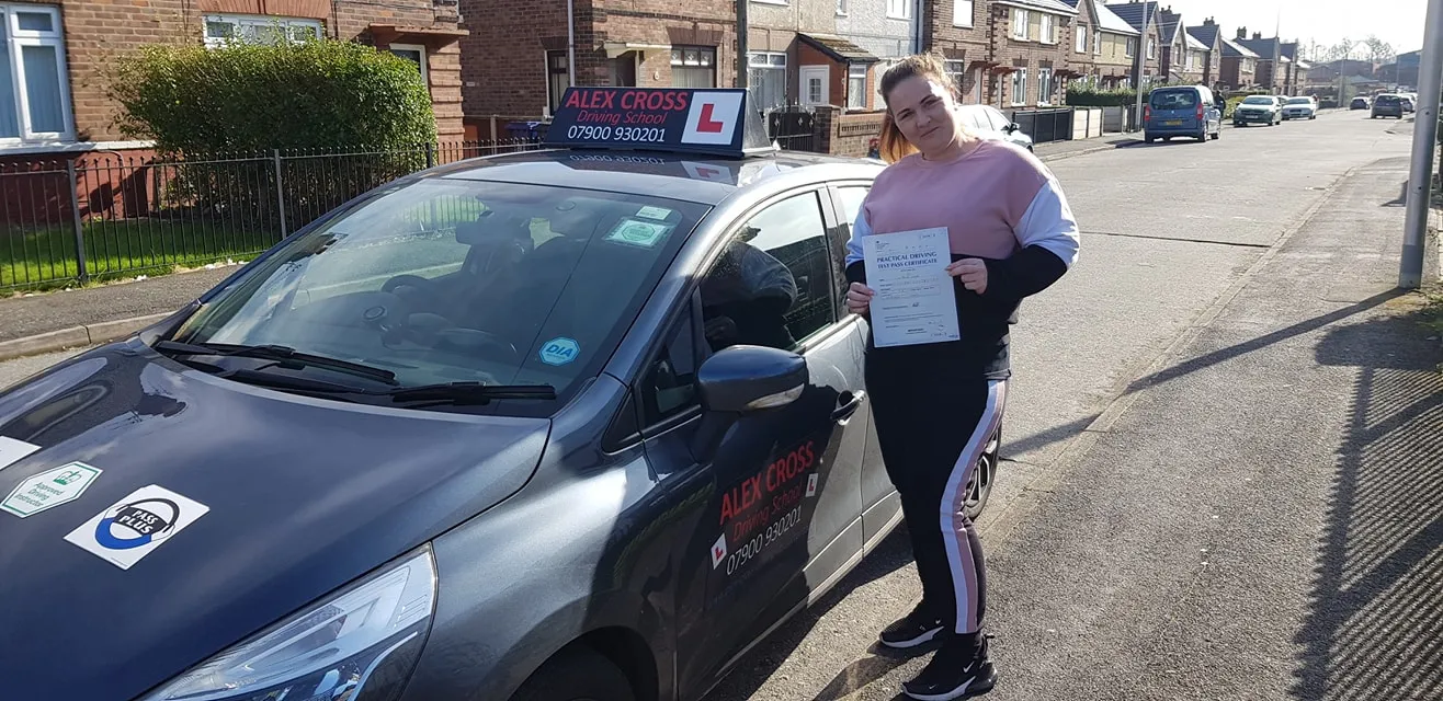 One of Alex's pupils holding her pass certificate beside the car