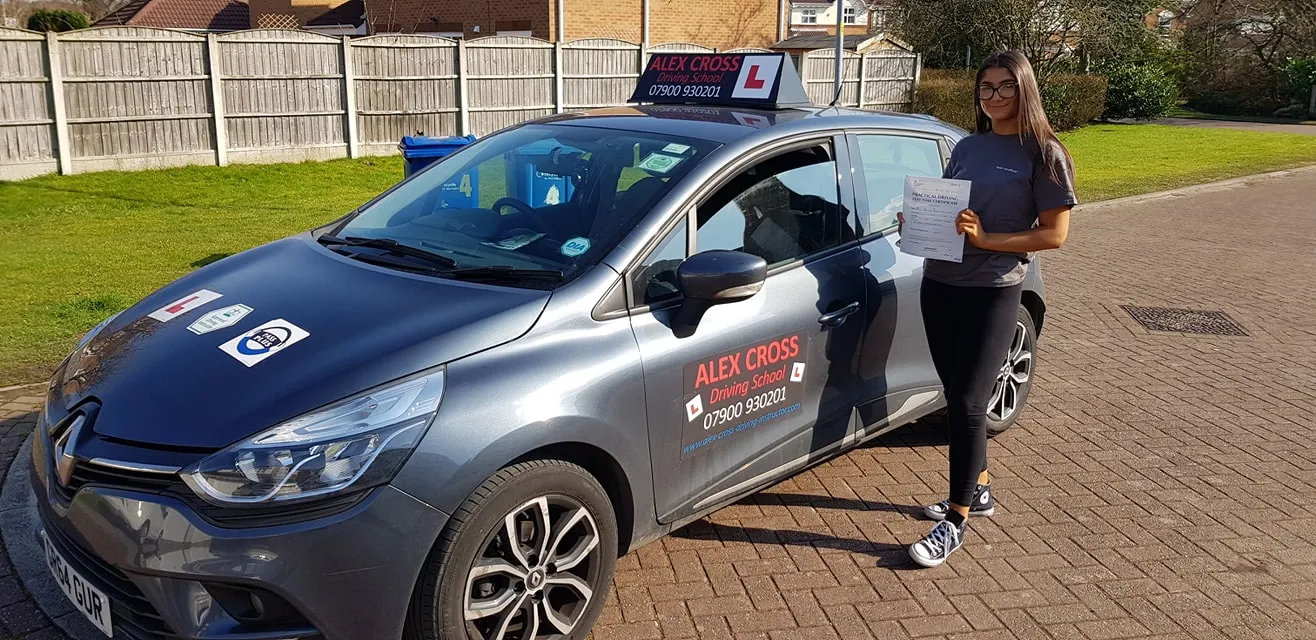 One of Alex's pupils holding her pass certificate beside the car