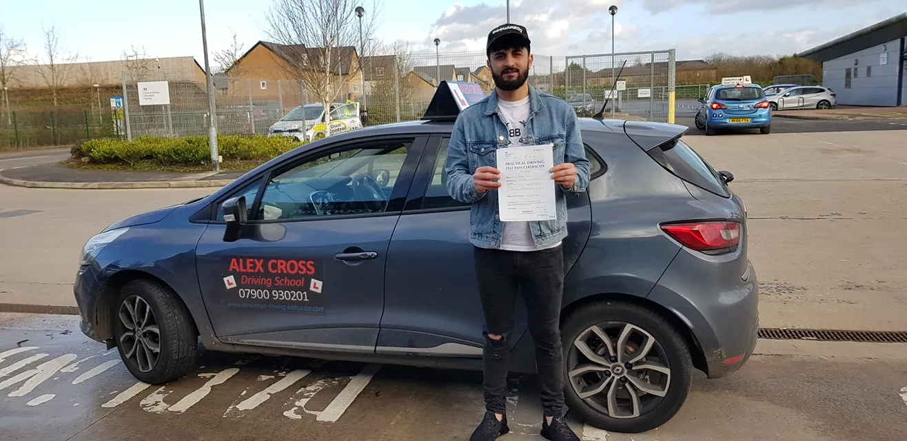 One of Alex's pupils holding his pass certificate beside the car