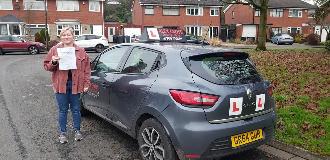 One of Alex's pupils holding her pass certificate beside the car
