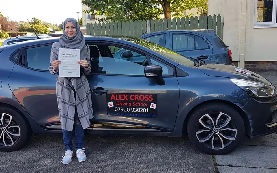 One of Alex's pupils holding her pass certificate beside the car
